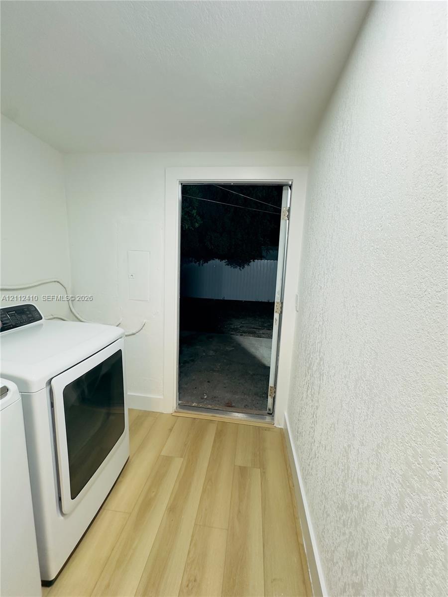 Utility space featuring wood-finish flooring, smooth-finish walls, and an exterior door
