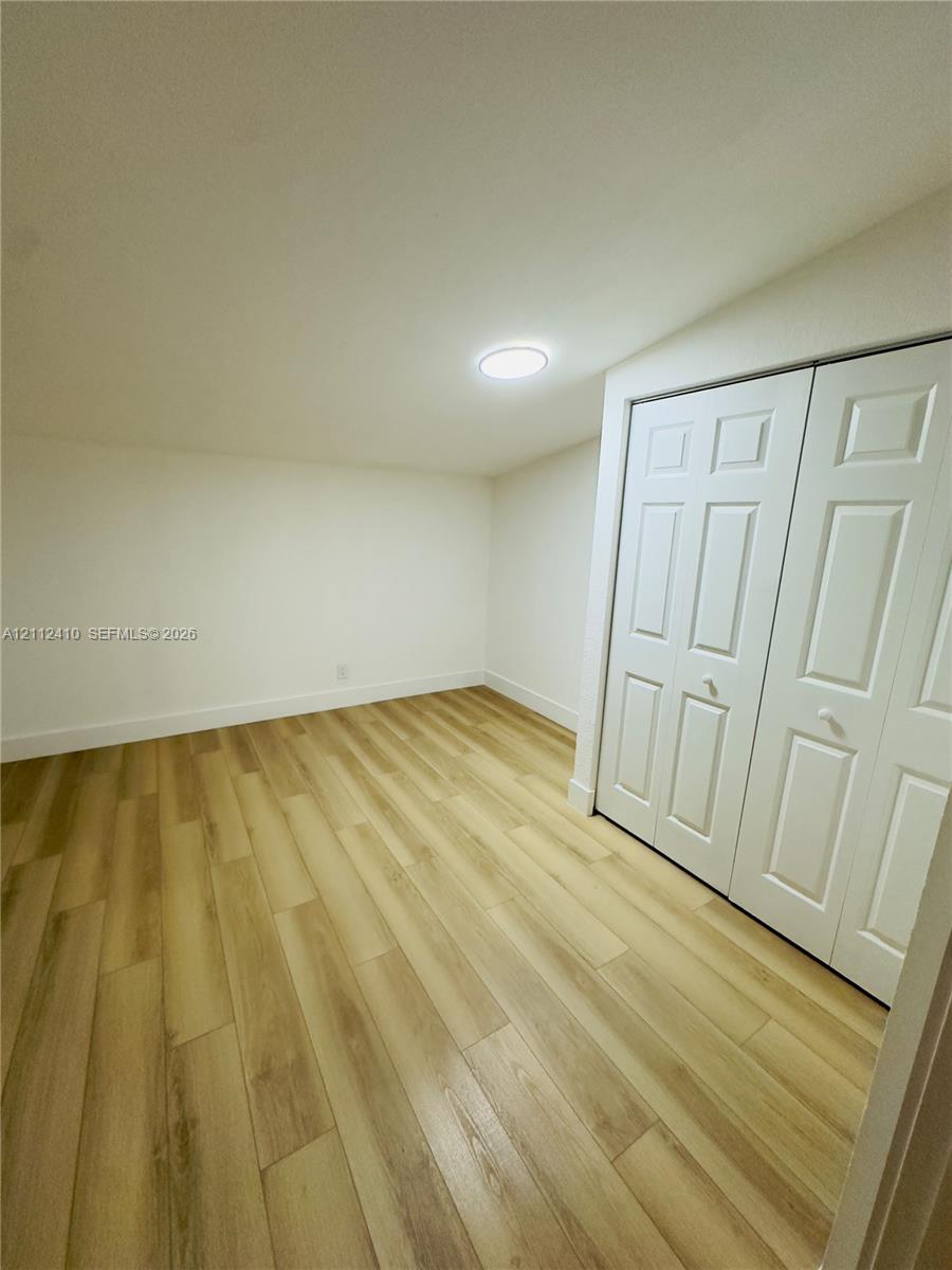 Neutral-toned wood-finish flooring, dual-panel closet doors, and recessed ceiling lighting