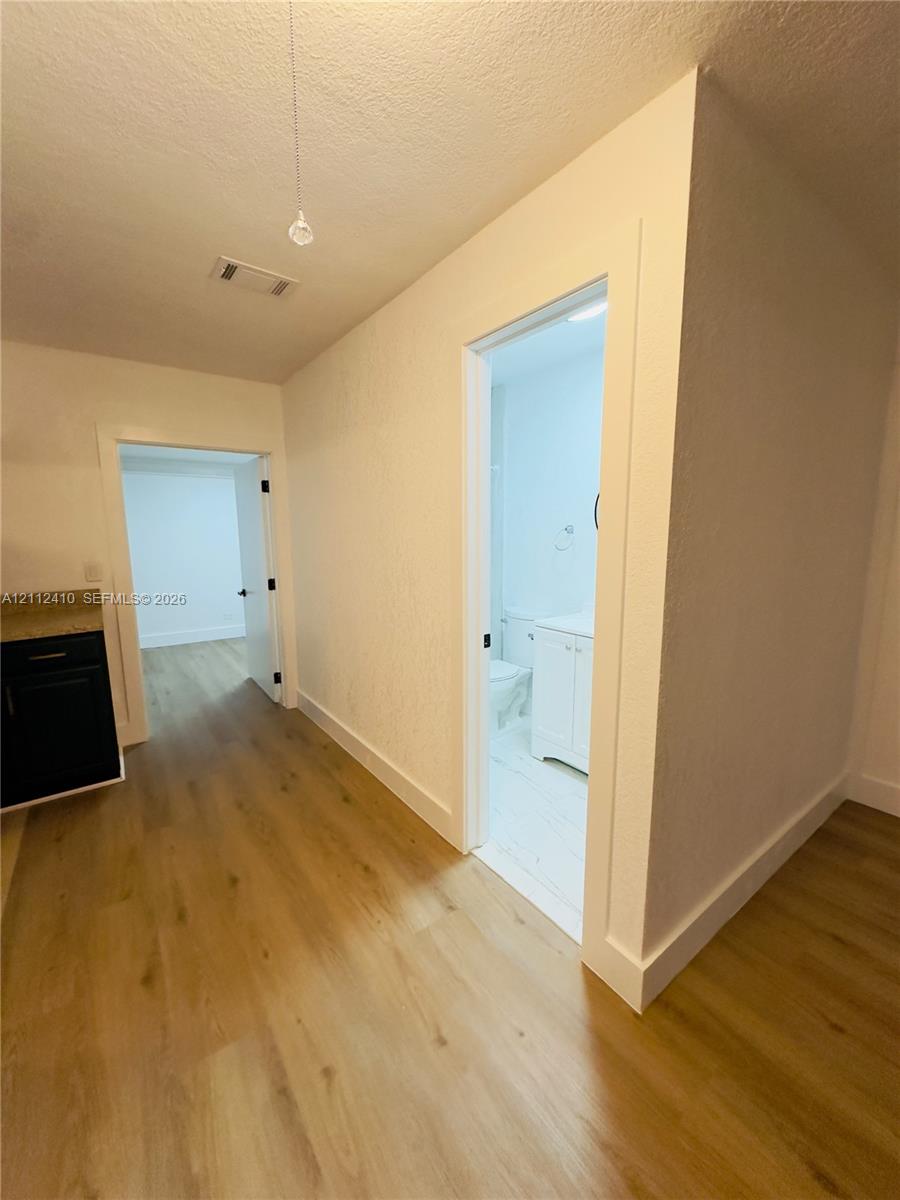 Wood-finish flooring throughout, dark cabinetry with stone-finish countertop, and white interior doors with matte black hardware