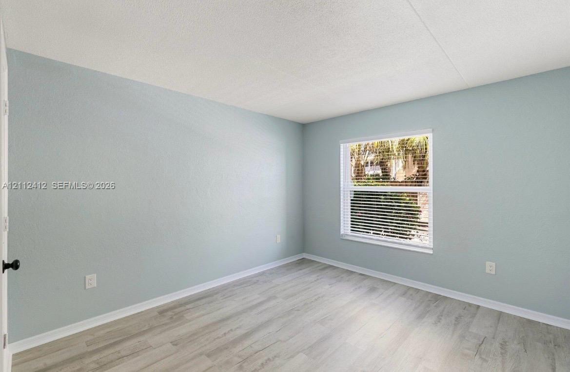 Neutral-toned wall paint, wood-finish flooring, and a single-pane window with adjustable horizontal blinds