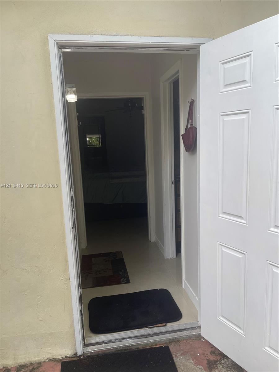 Six-panel white entry door with light-colored interior walls and neutral-tone flooring