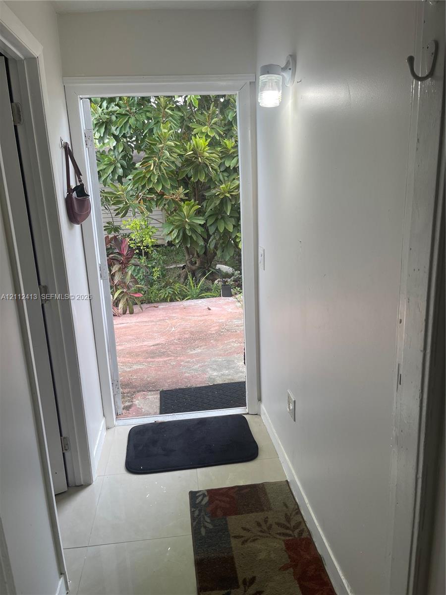 Entrance featuring light-toned tile flooring and a wall-mounted fixture