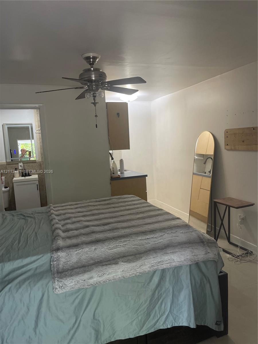 Room featuring a ceiling fan with integrated lighting, wood-finish cabinetry, and a pedestal sink with a dark-finished faucet