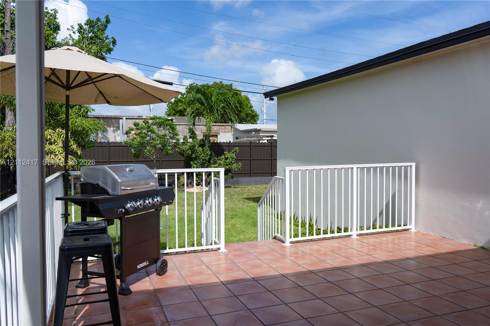 Tiled patio featuring a white metal railing and a fenced backyard