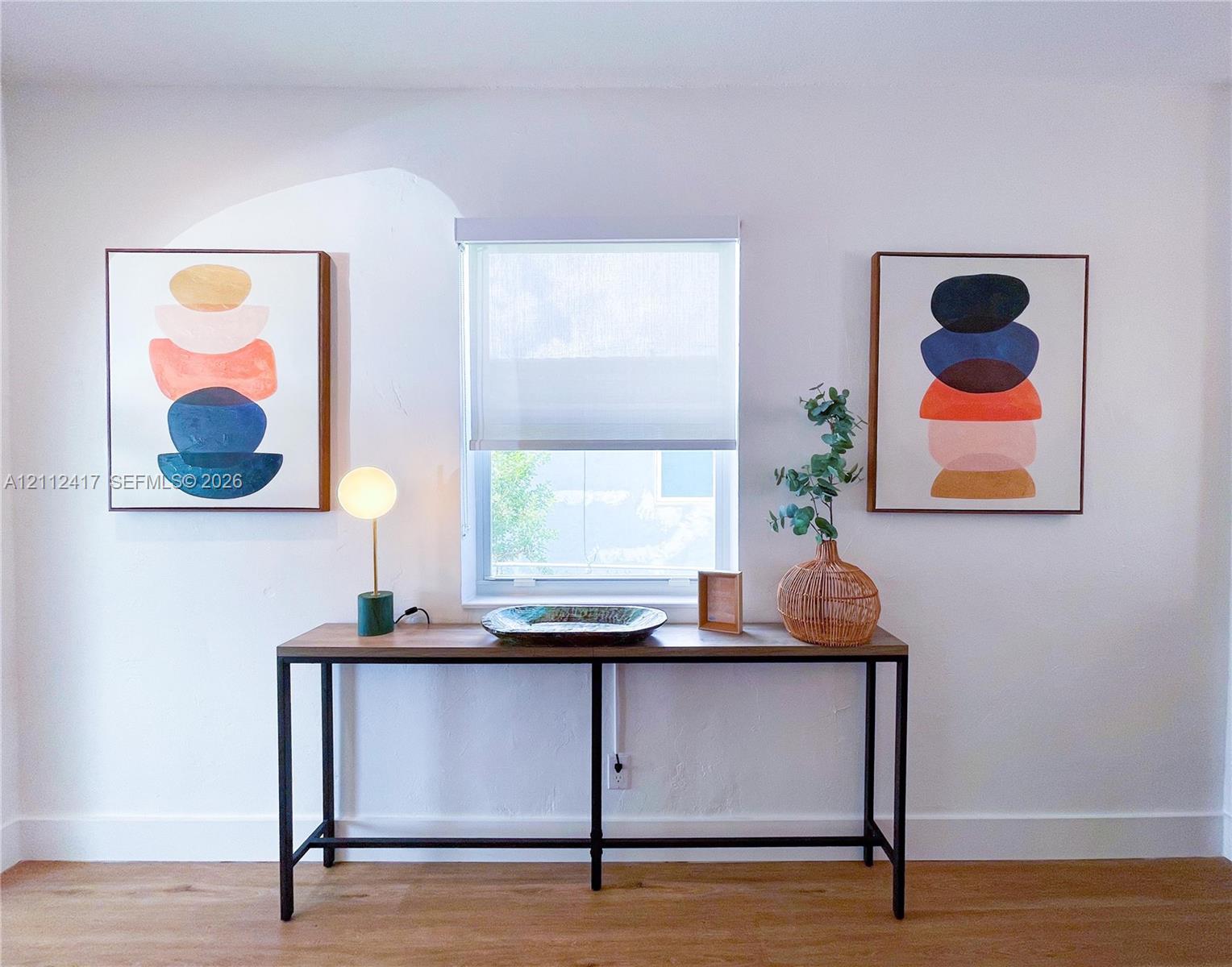 Single-hung window with a neutral roller shade, complemented by light-toned wood-finish flooring
