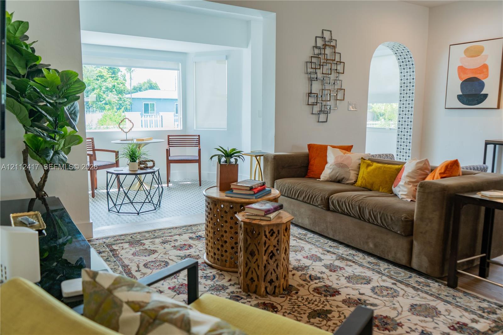 Living area featuring an arched entryway with decorative tiling, expansive windows, and light-toned flooring