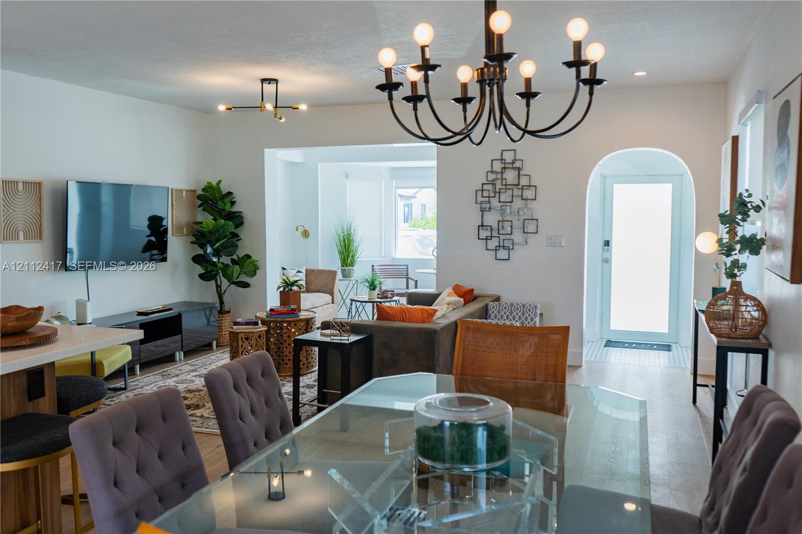 Open-concept living space featuring wood-finish flooring, a wrought iron chandelier, recessed lighting, and an arched entryway