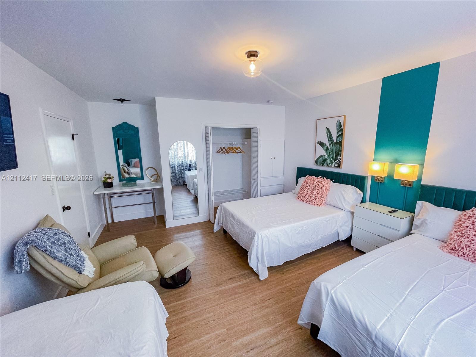 Spacious room featuring wood-finish flooring, built-in shelving, a walk-in closet with integrated storage, and decorative wall-mounted accent panels