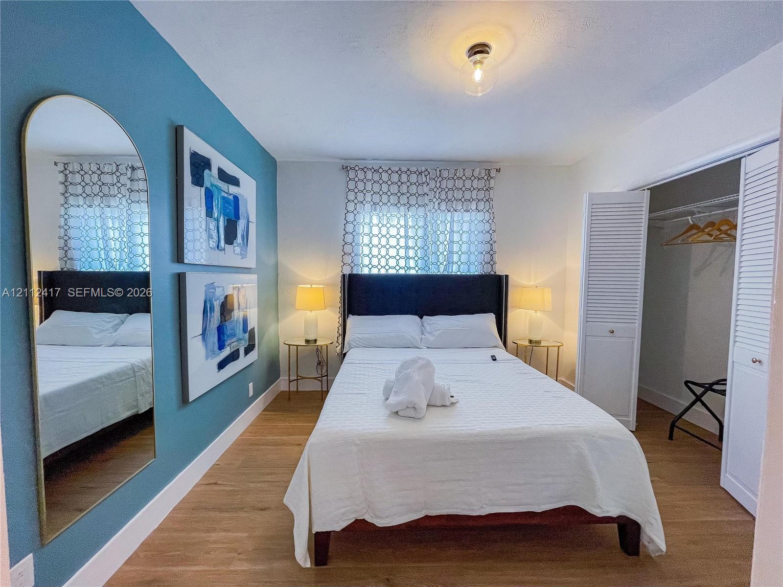 Room featuring wood-finish flooring, an accent wall, and a closet with louvered bi-fold doors