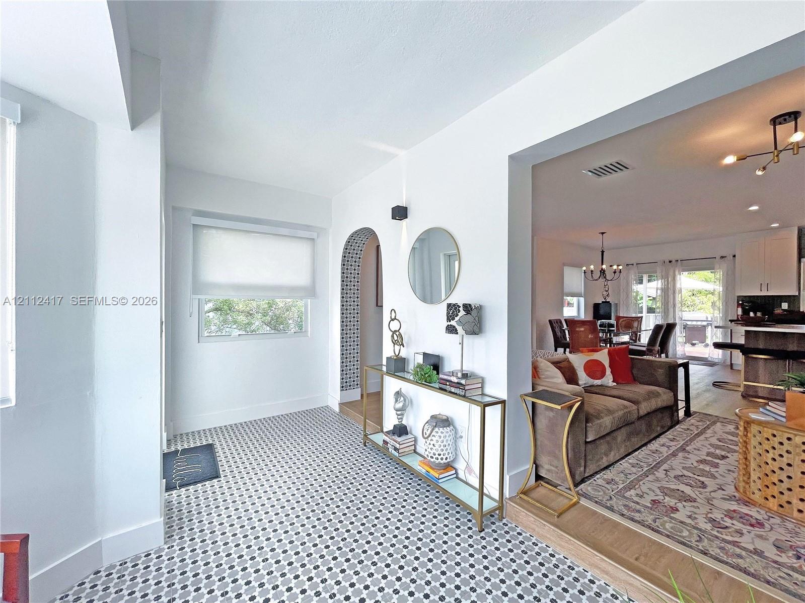 Geometric tile flooring, arched entryway with decorative mosaic tile detailing, and wood-finish flooring