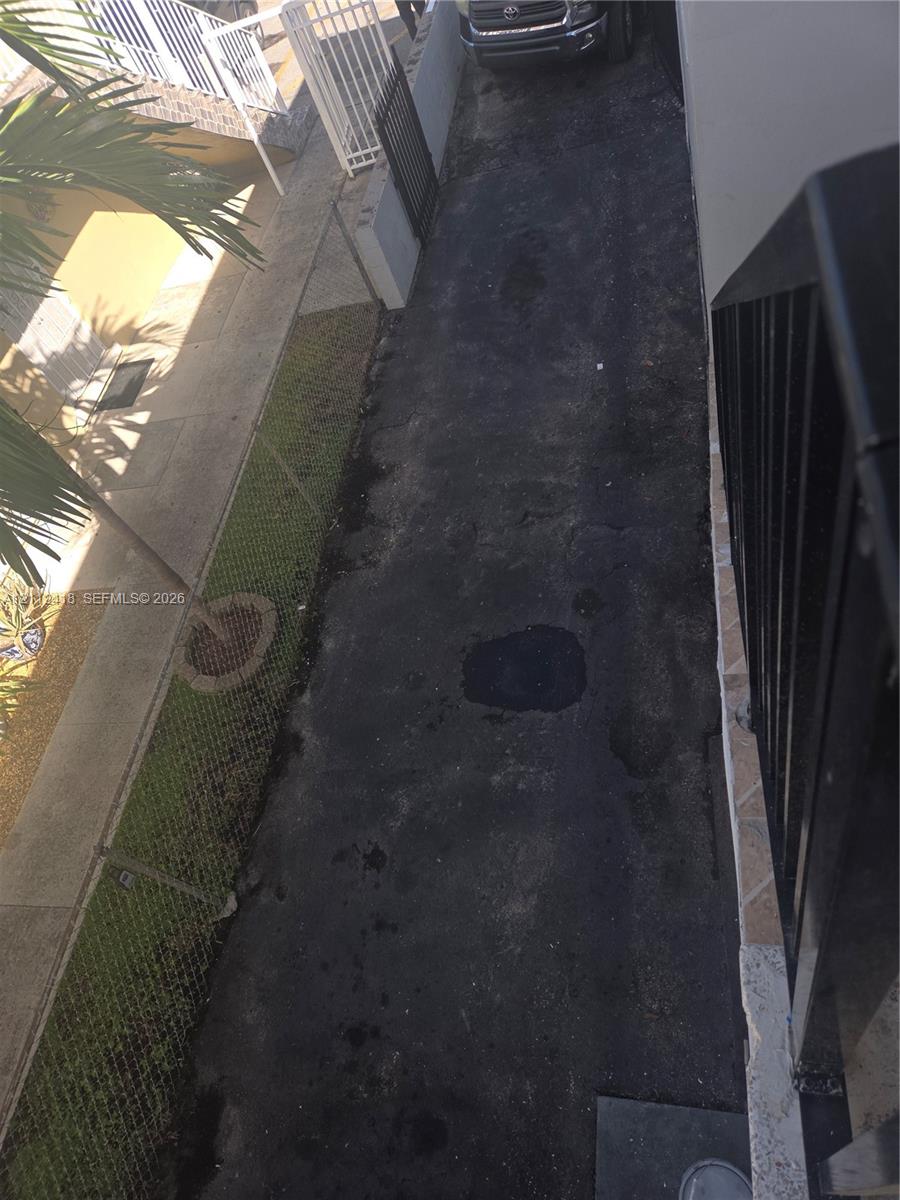 Asphalt driveway featuring 2 parking spaces a chain-link fence