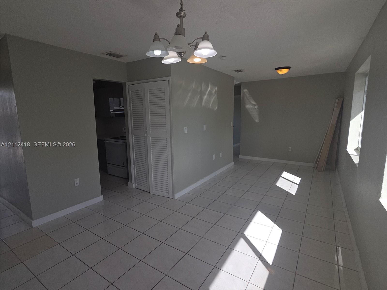 Ceramic tile flooring, five-light brushed nickel chandelier, recessed ceiling lighting, and louvered double-door closet Ceramic tile flooring, five-light brushed nickel chandelier, recessed ceiling lighting, and louvered double-door closet