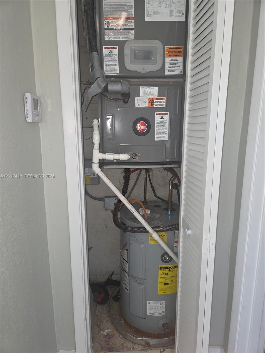 Utility closet featuring a dedicated HVAC unit and a water heater enclosed by a louvered door Utility closet featuring a dedicated HVAC unit and a water heater enclosed by a louvered door