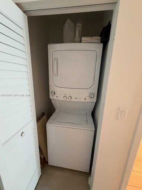 Laundry closet featuring a white stacked washer and dryer unit concealed behind a louvered bi-fold door
