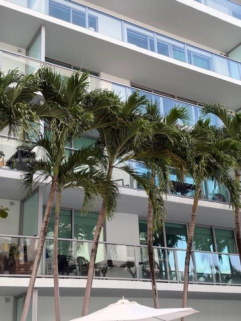 Multi-story exterior featuring tiered glass balconies and mature palm trees