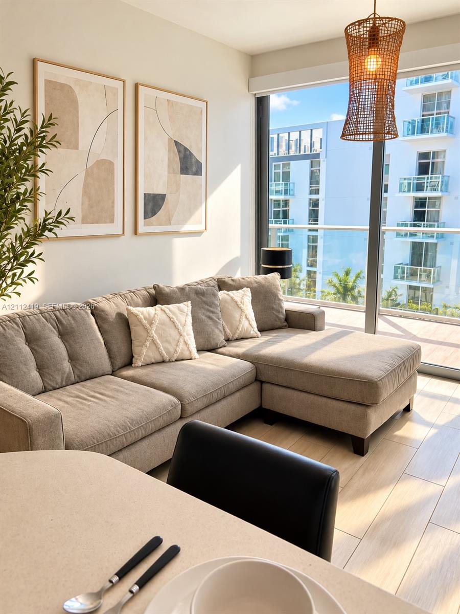 Floor-to-ceiling glass sliding doors, wood-finish flooring, woven pendant light fixture, and balcony access