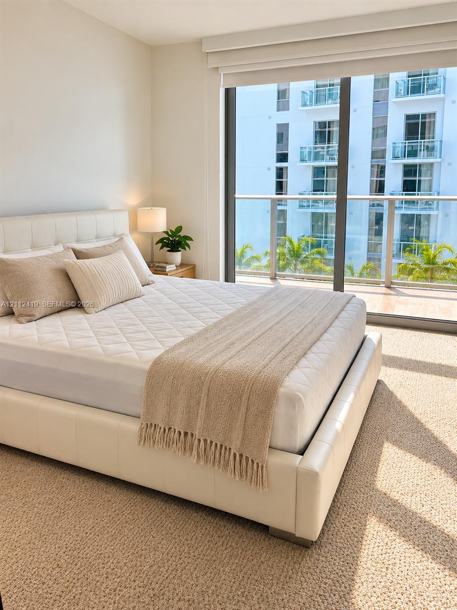 Floor-to-ceiling windows featuring a glass-railing balcony, neutral wall-to-wall carpeting, and integrated window treatments