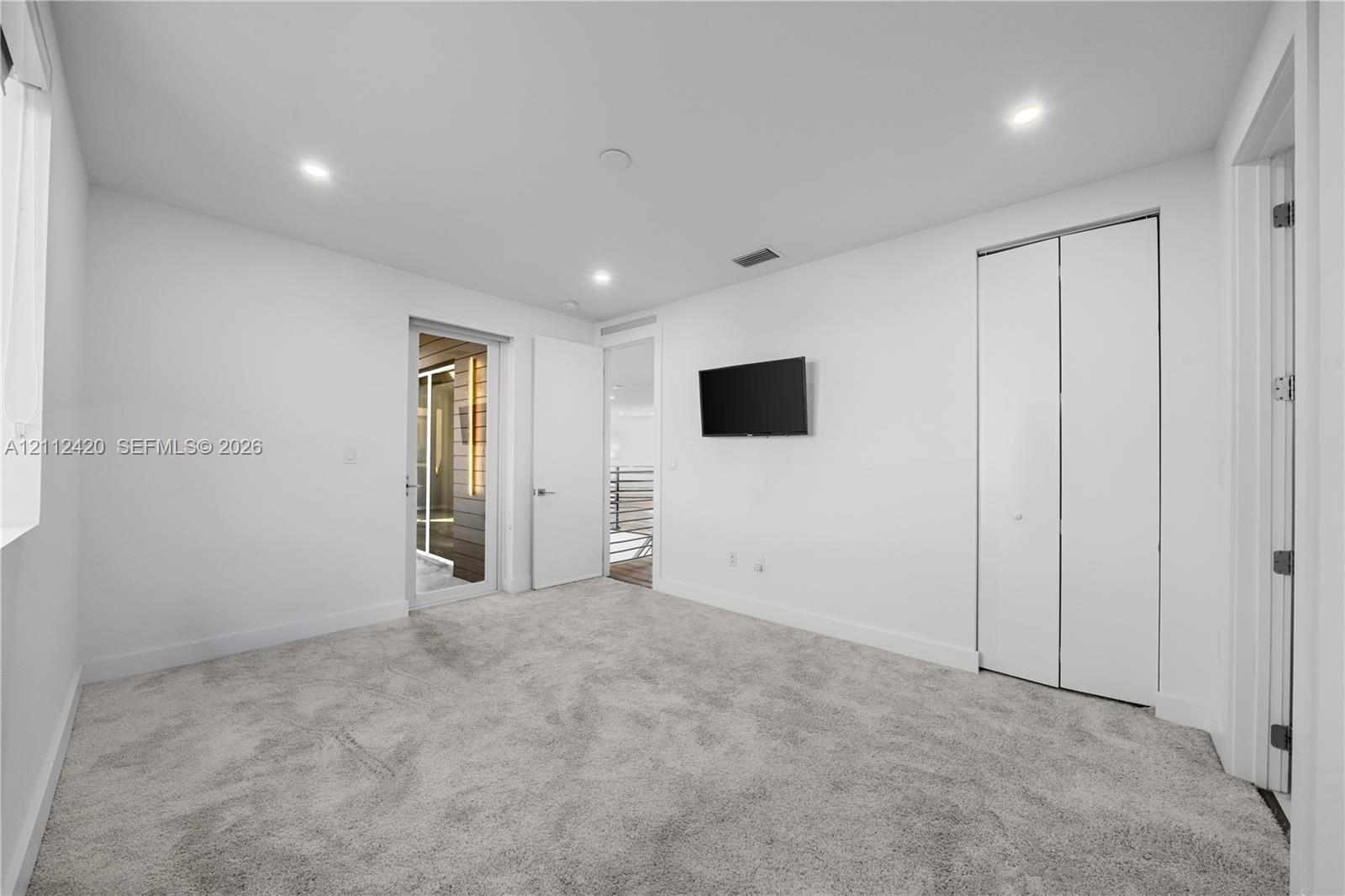 Neutral wall tones with recessed LED lighting, wall-to-wall carpeting, and a double-door closet