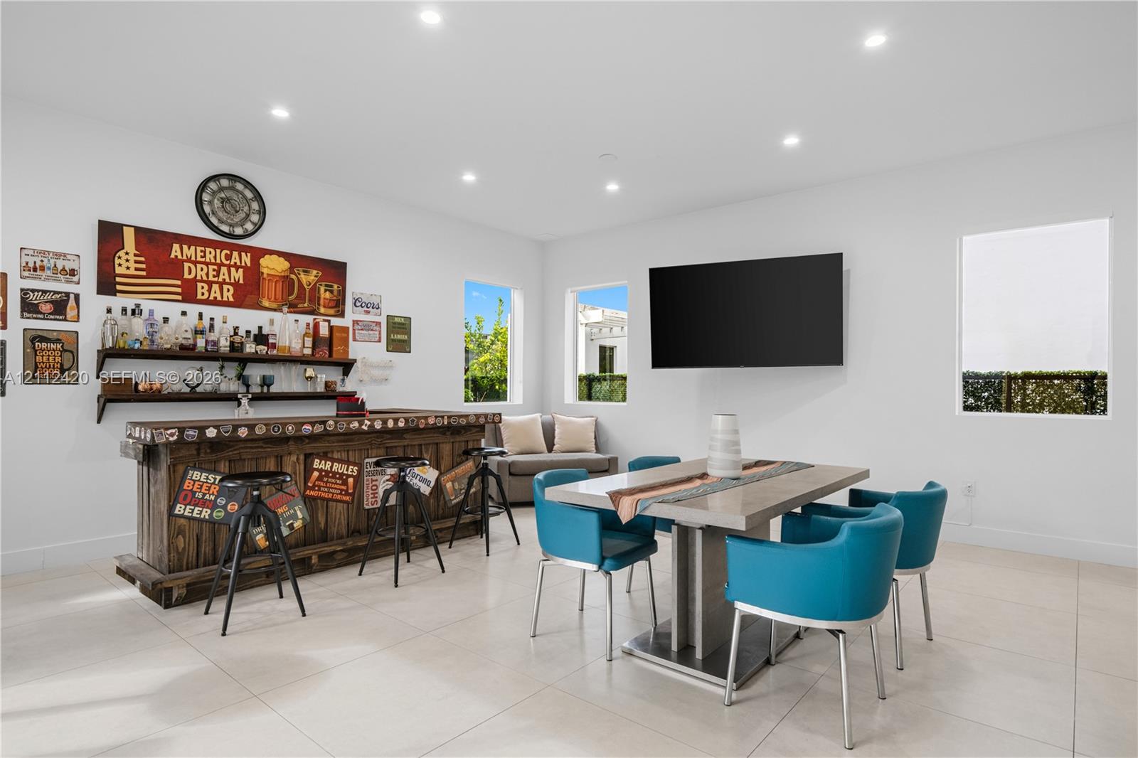 Recessed lighting, large-format tile flooring, and custom wood-finished wet bar with open shelving