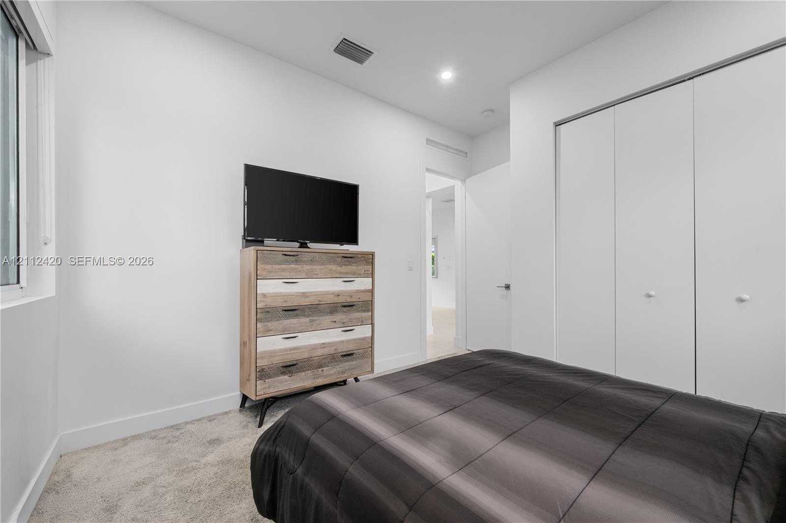 Interior space featuring neutral wall tones, recessed lighting, carpeted flooring, and a floor-to-ceiling multi-panel sliding door closet