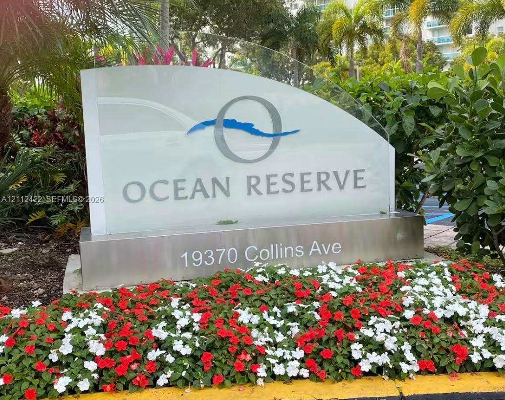 Ocean Reserve monument signage featuring a glass-panel display with brushed-metal base and surrounding manicured garden beds