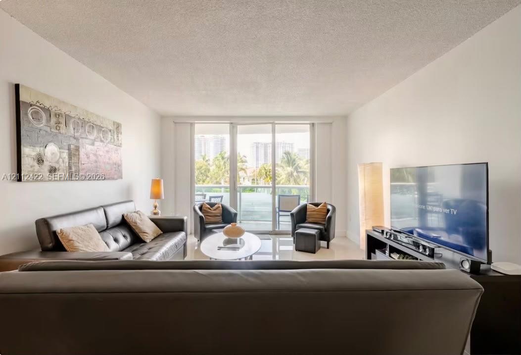Open-concept living space featuring high-gloss tile flooring and floor-to-ceiling glass sliding doors providing external access