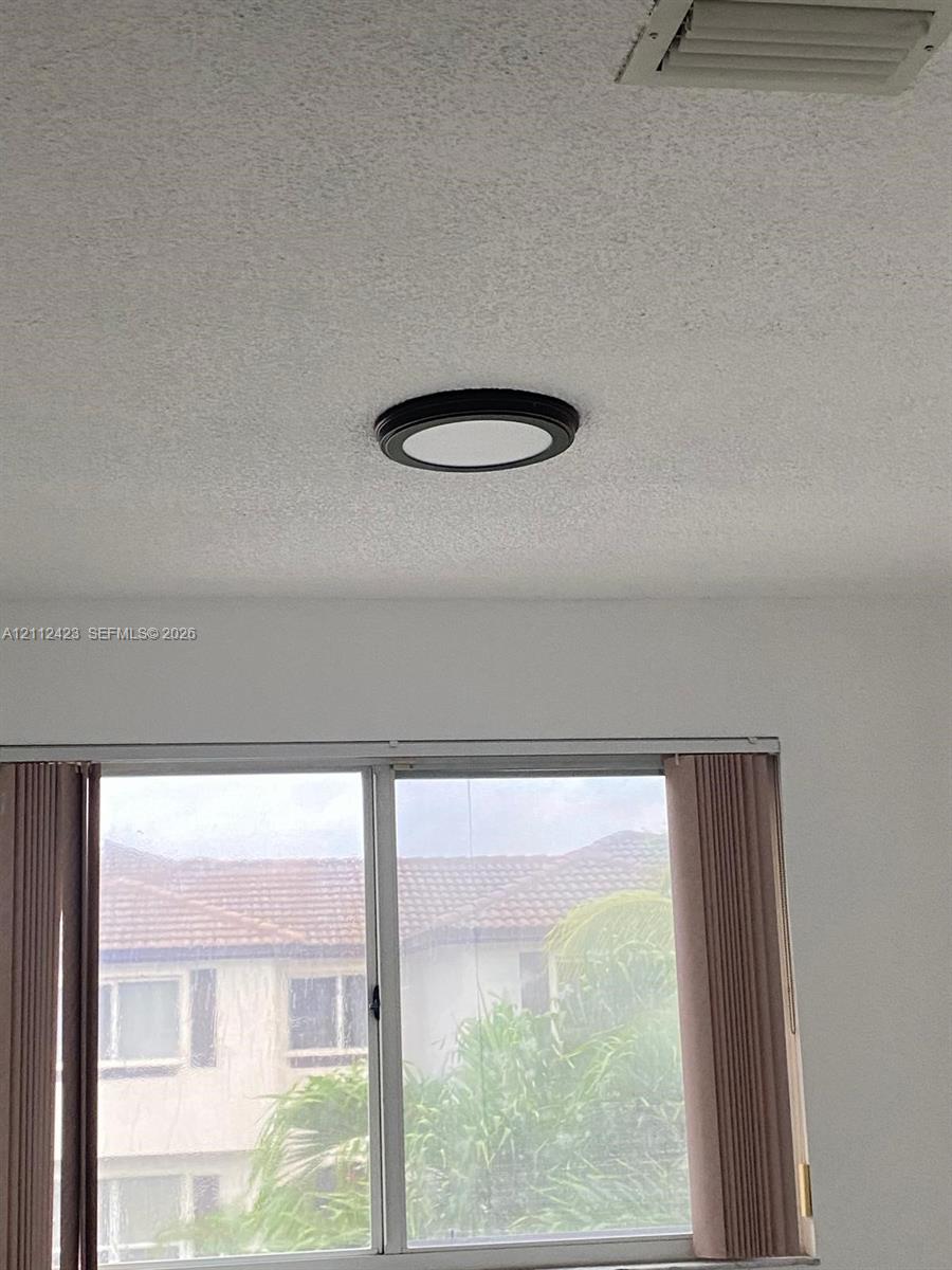 Flush-mount circular ceiling light fixture with a matte black frame and textured ceiling finish