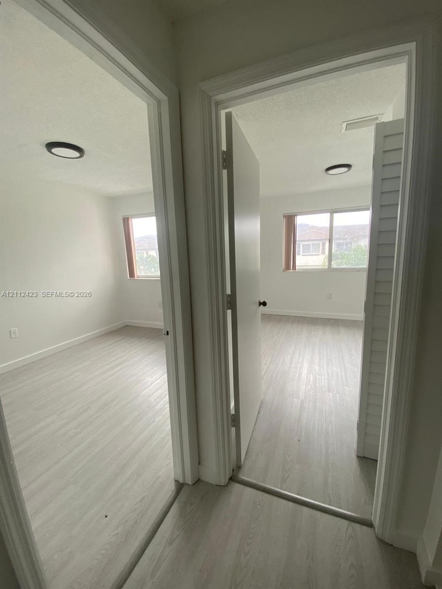 Rooms featuring wood-finish flooring, sliding windows, and flush-mount lighting fixtures, including a room with bi-fold closet doors