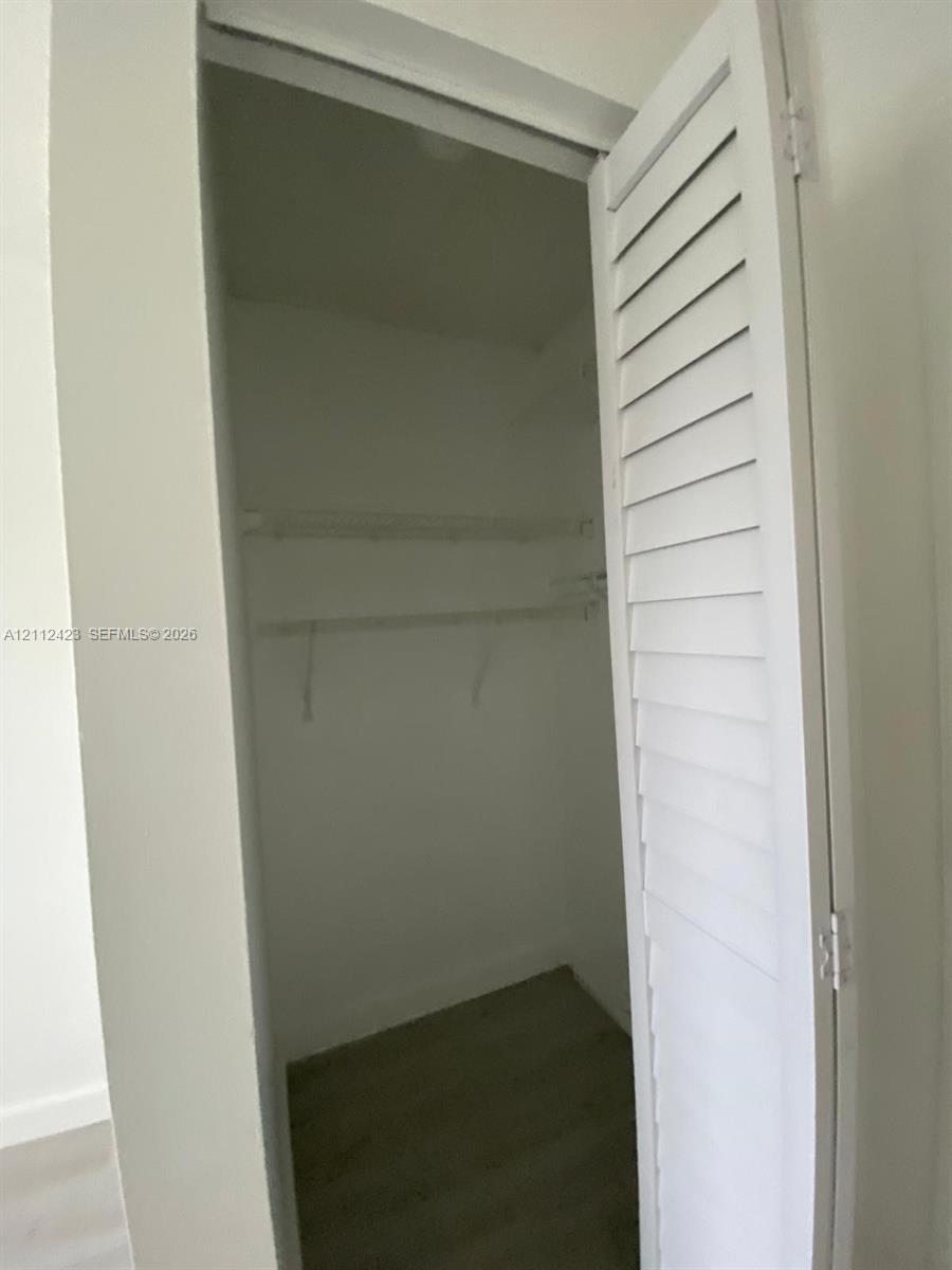 Closet featuring white louvered doors, built-in shelving, and a hanging rod