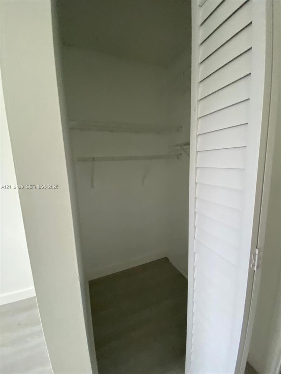 Closet featuring louvered bi-fold doors, wood-finish flooring, and built-in shelving