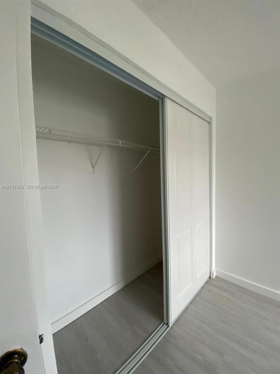 Closet featuring white sliding doors and integrated wire shelving over wood-finish flooring