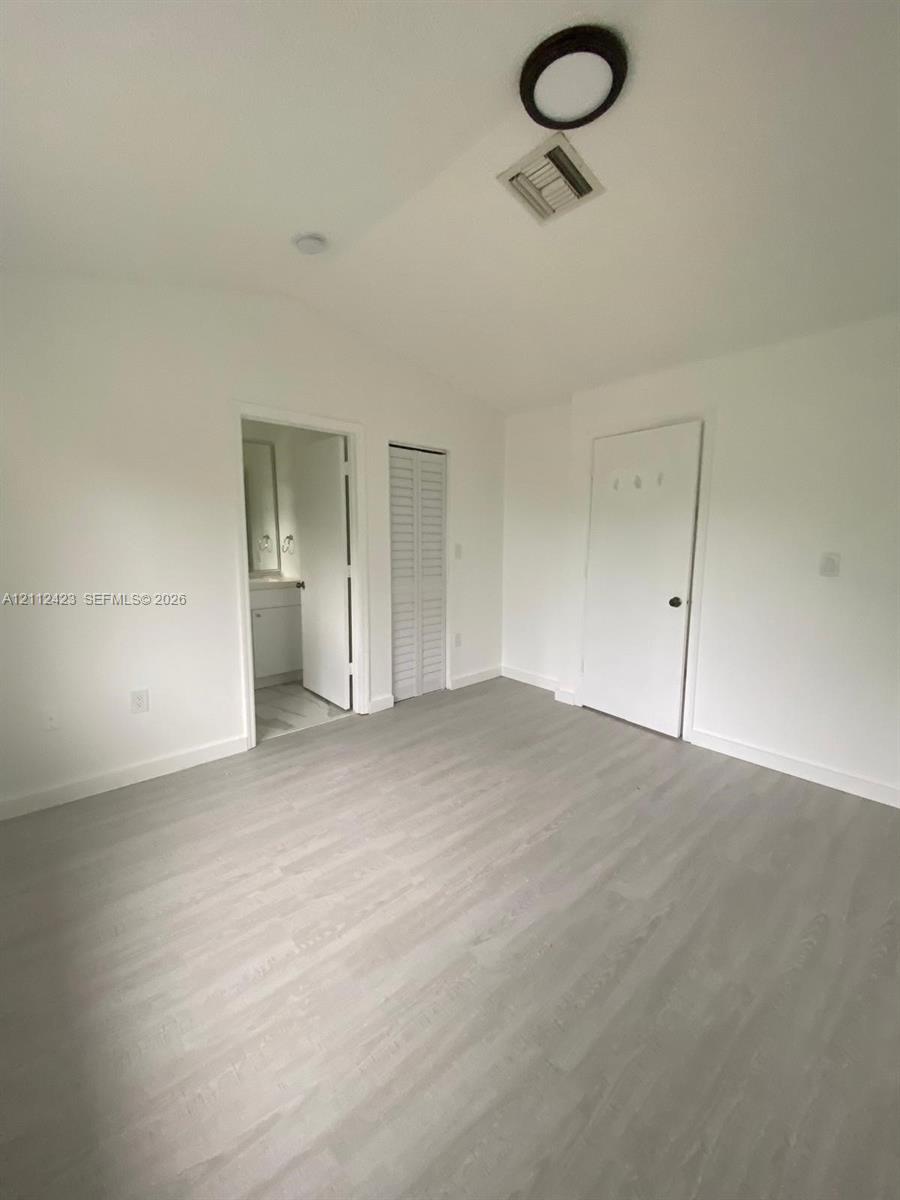 Neutral-toned wood-finish flooring, vaulted ceilings, and louvered closet doors