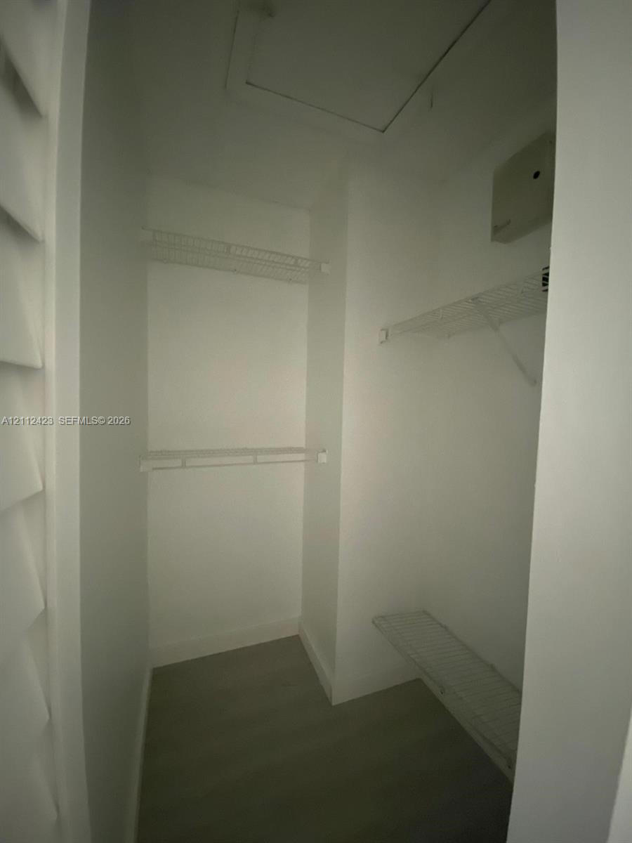 Storage closet featuring wire shelving and wood-finish flooring