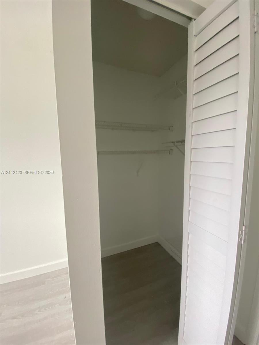 Closet featuring white louvered doors, wood-finish flooring, and built-in wire shelving