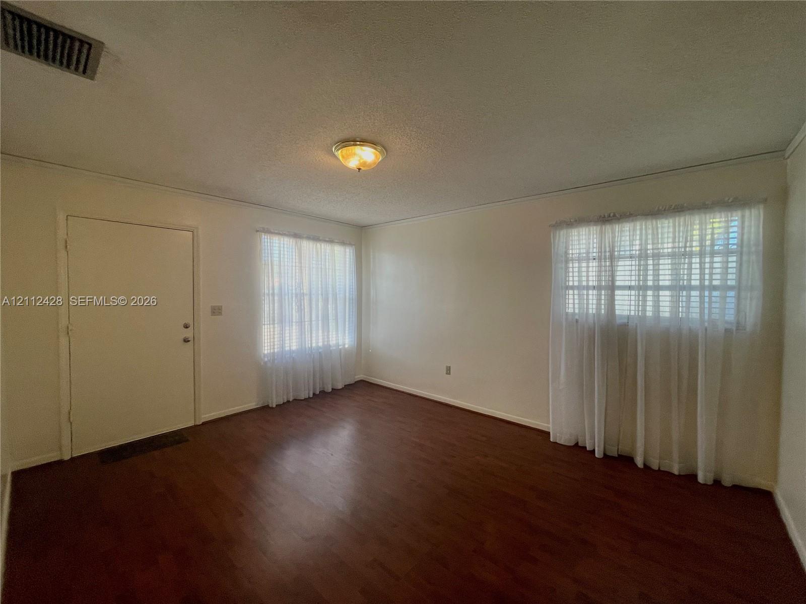 Interior space featuring wood-finish flooring, two windows with natural light, and a central ceiling-mounted light fixture Interior space featuring wood-finish flooring, two windows with natural light, and a central ceiling-mounted light fixture