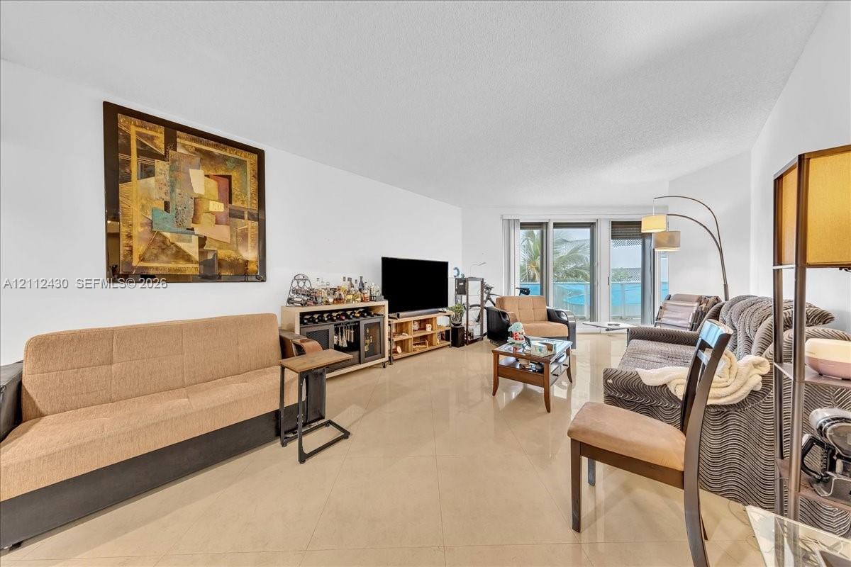Living area featuring large-format ceramic tile flooring and floor-to-ceiling glass sliding doors Living area featuring large-format ceramic tile flooring and floor-to-ceiling glass sliding doors
