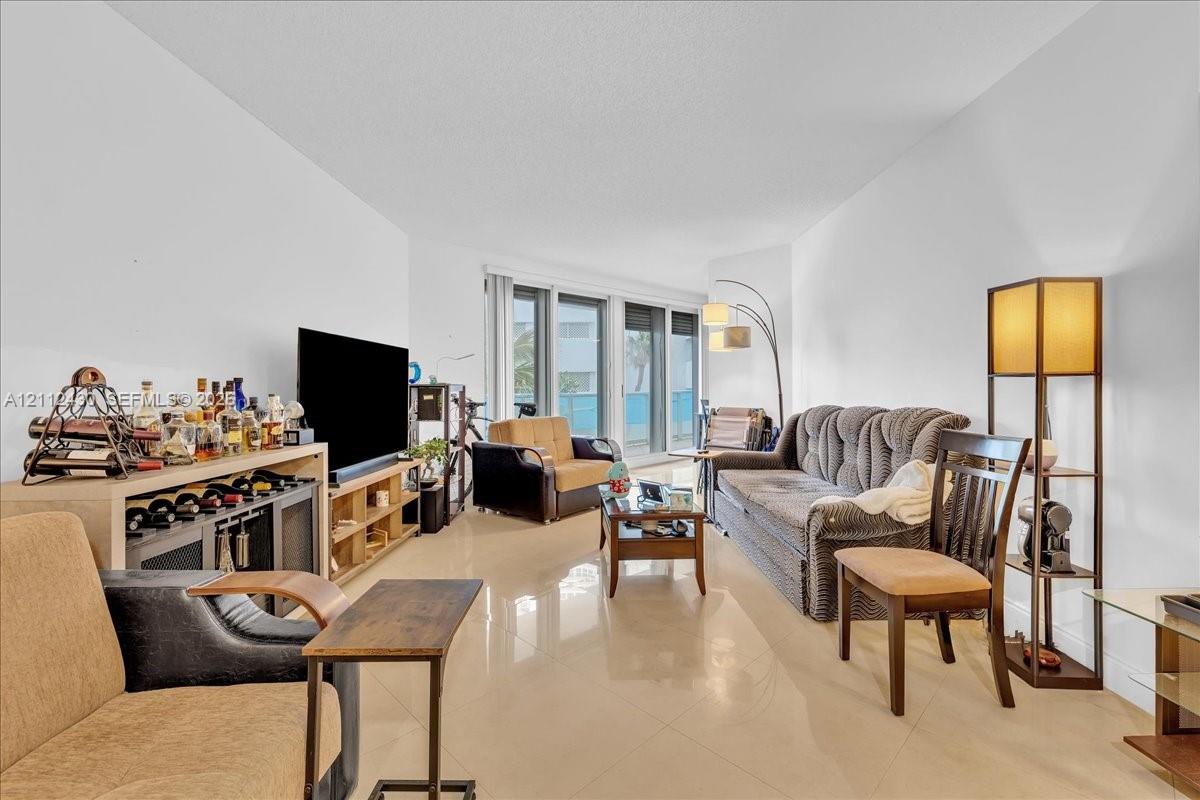 Living area featuring polished tile flooring, neutral walls, and large floor-to-ceiling glass sliding doors Living area featuring polished tile flooring, neutral walls, and large floor-to-ceiling glass sliding doors