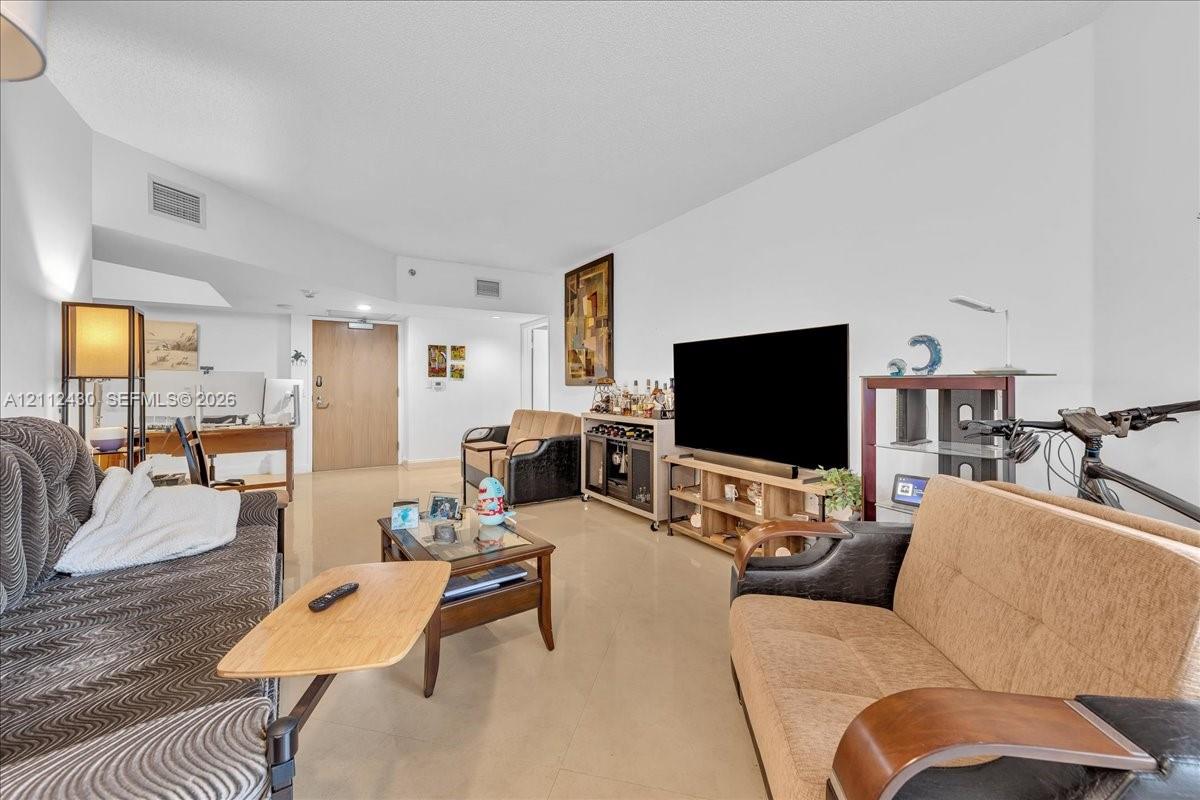 Open-concept interior featuring neutral-toned tile flooring and vaulted ceilings Open-concept interior featuring neutral-toned tile flooring and vaulted ceilings