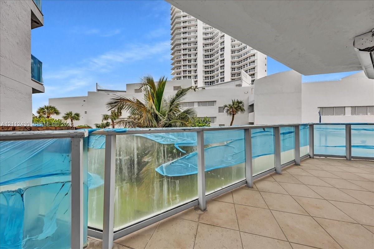 Covered balcony featuring tile flooring and a glass railing with metal framing