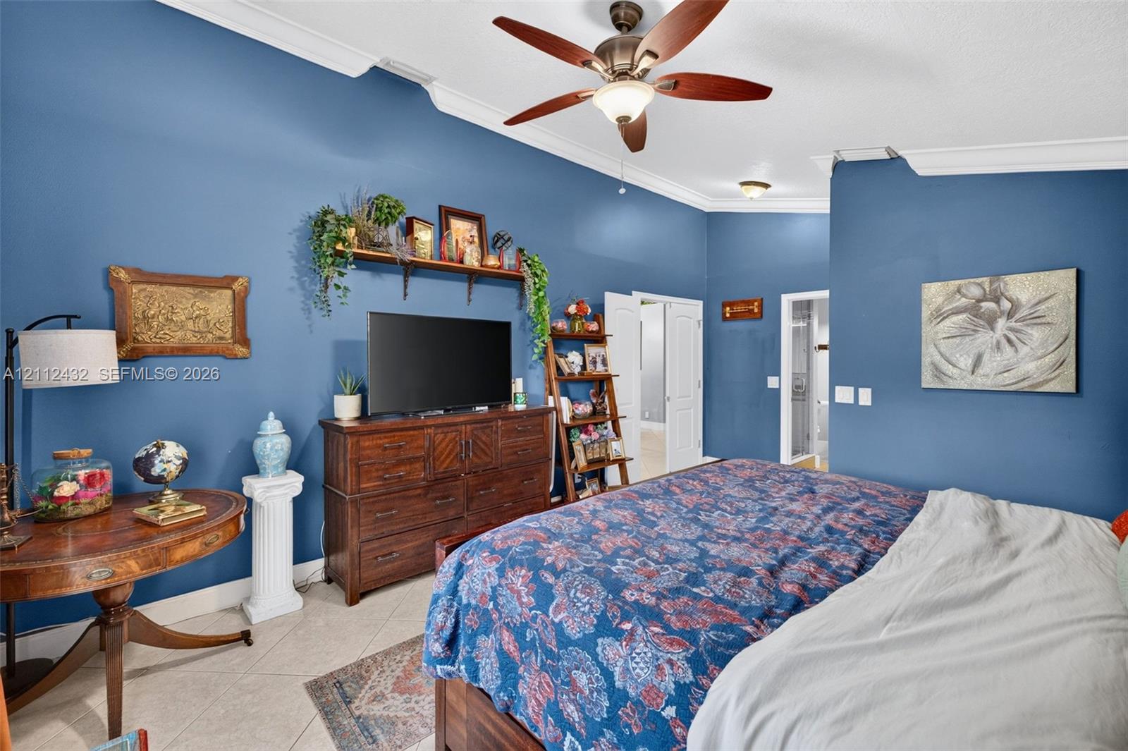 Vaulted ceilings with crown molding, ceiling fan with light kit, and tile flooring