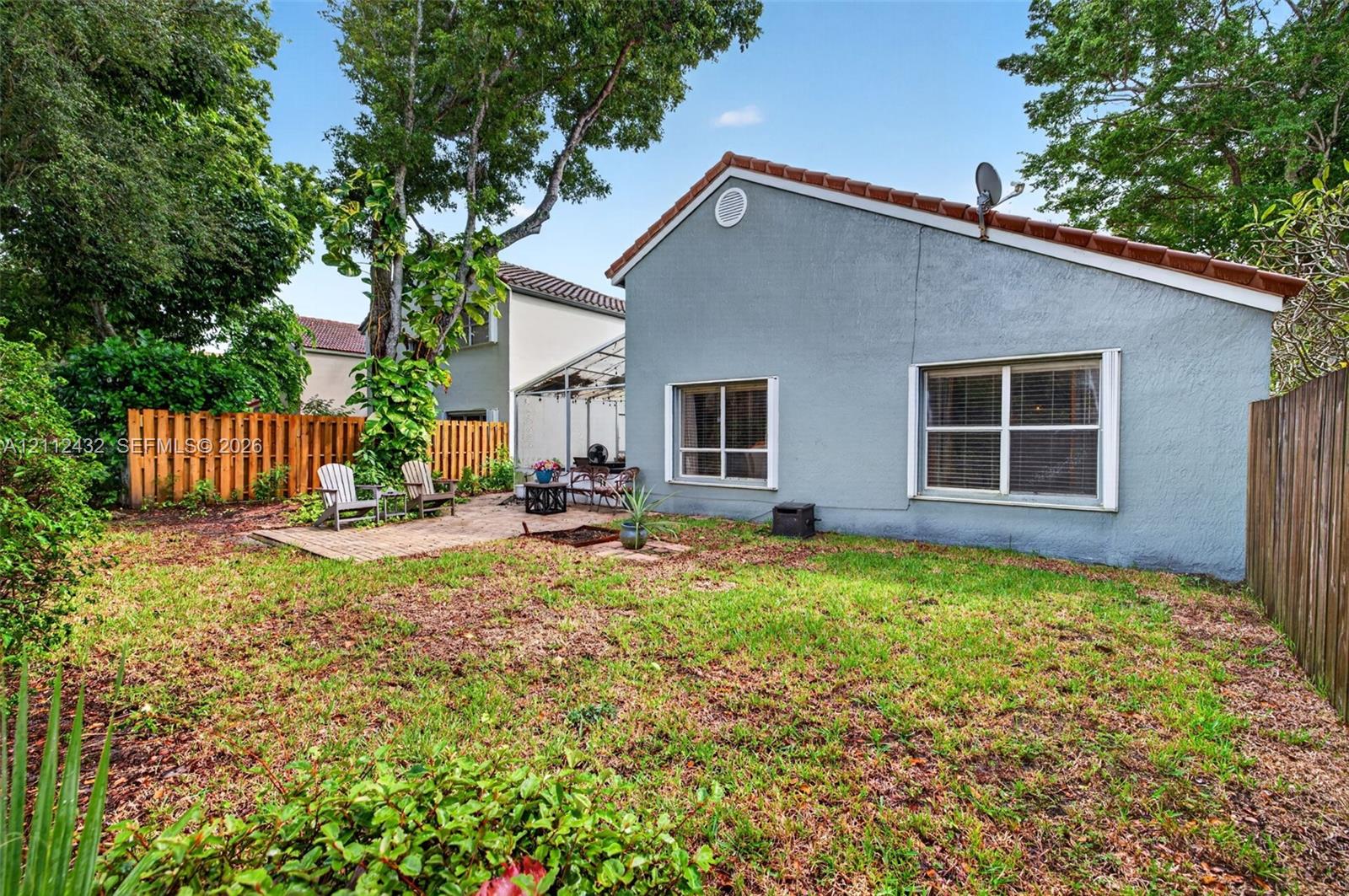 Rear exterior featuring stucco siding, tile roof, brick paver patio