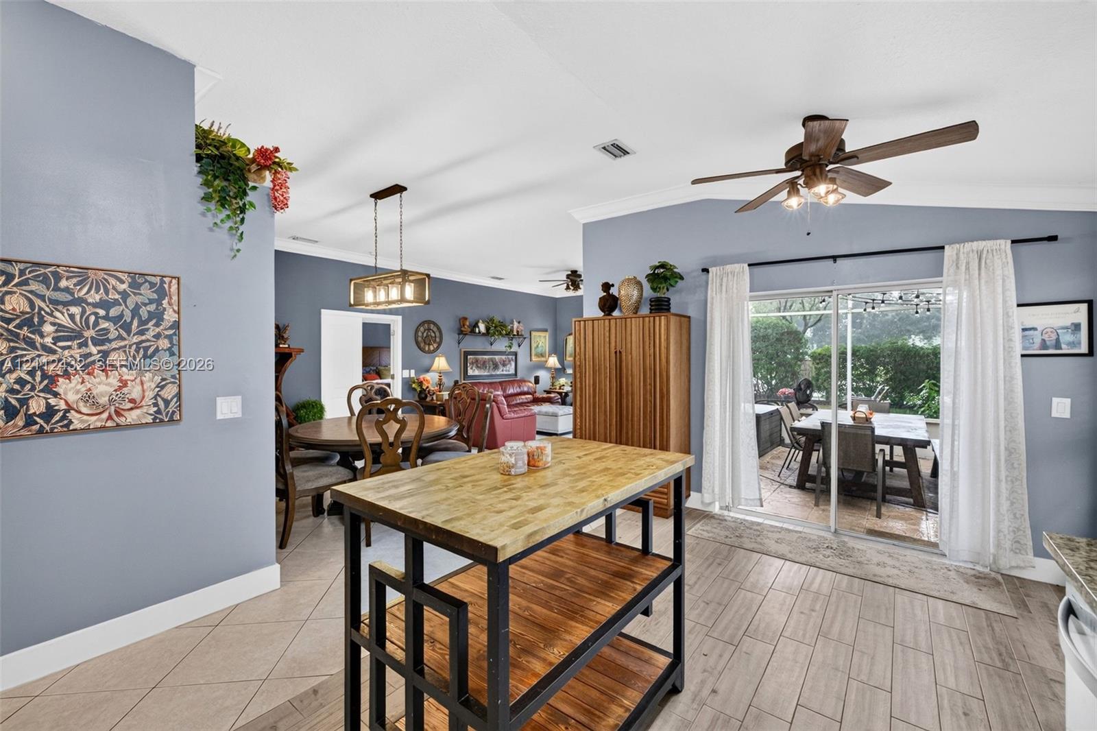 Open kitchen area featuring vaulted ceilings, wood-look tile flooring, sliding glass doors, and a multi-light metal chandelier