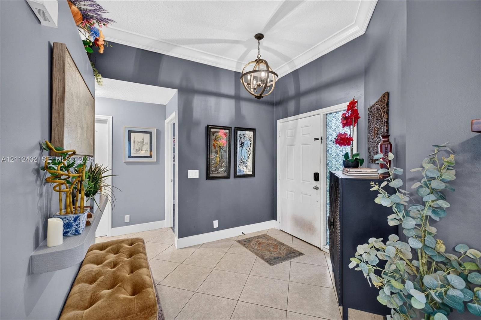 Foyer featuring large-format ceramic tile flooring, crown molding, a decorative orb chandelier