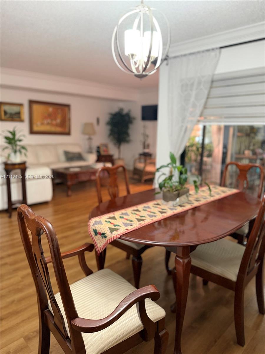 Open floor plan featuring wood-finish flooring, crown molding, and a spherical metal chandelier with multi-light fixture Open floor plan featuring wood-finish flooring, crown molding, and a spherical metal chandelier with multi-light fixture
