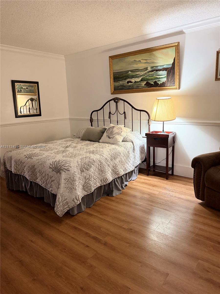 Room featuring wood-finish flooring, chair rail molding, and textured ceiling finish Room featuring wood-finish flooring, chair rail molding, and textured ceiling finish