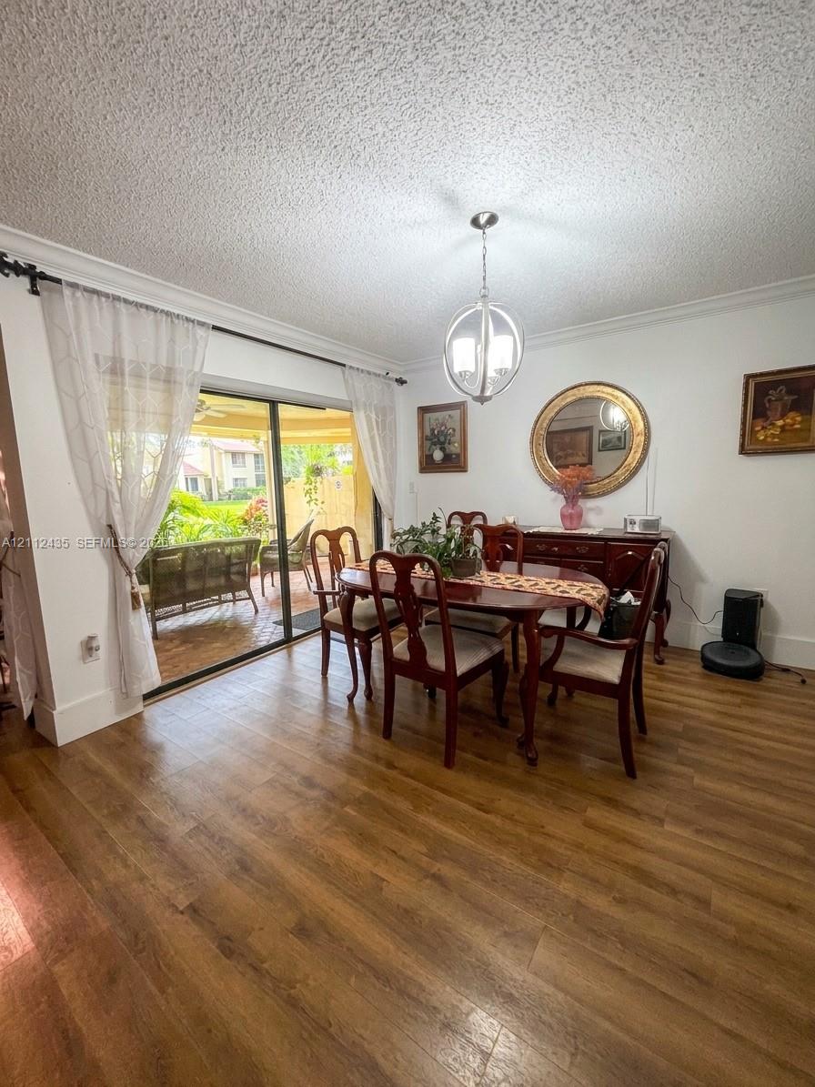 Wood-finish flooring, sliding glass door, spherical metal pendant lighting, and crown molding Wood-finish flooring, sliding glass door, spherical metal pendant lighting, and crown molding