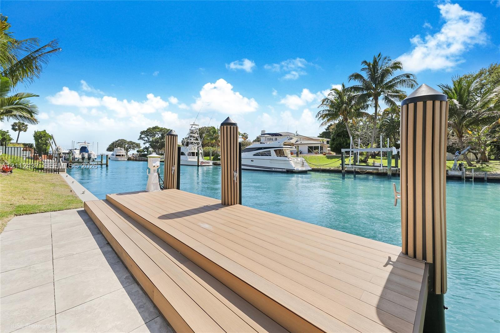 Waterfront dock featuring composite decking, integrated piling covers, and a paved concrete approach