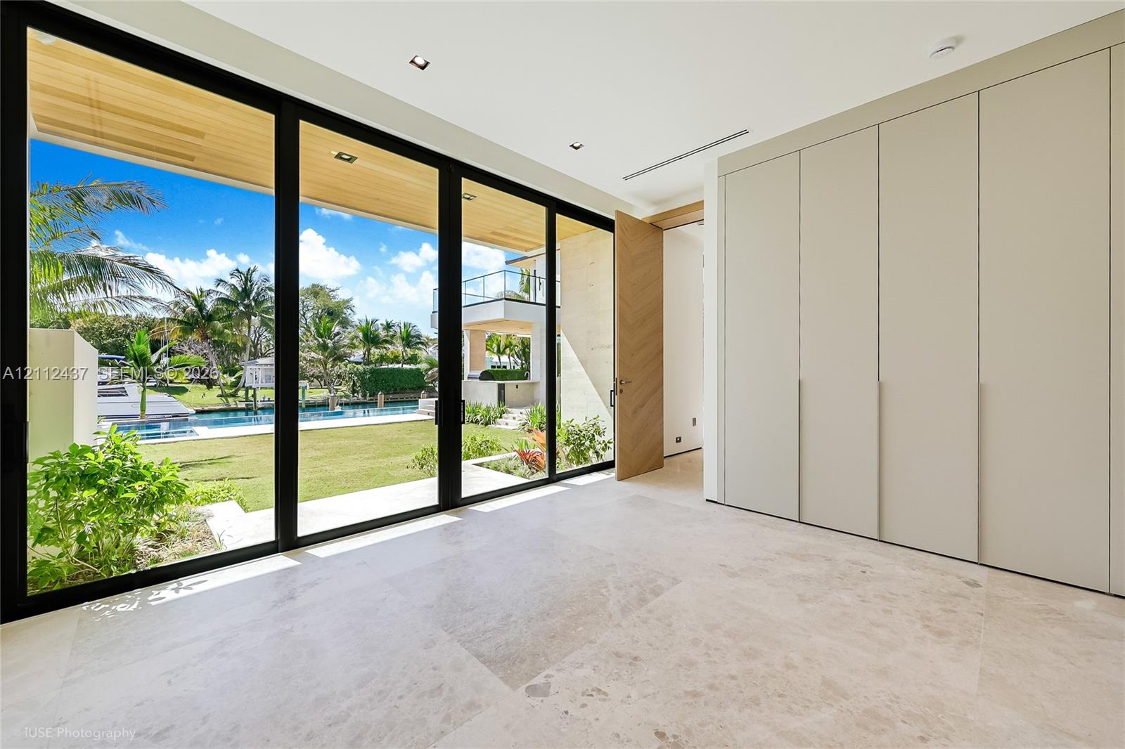 Floor-to-ceiling multi-panel glass doors, stone tile flooring, floor-to-ceiling integrated cabinetry, recessed lighting, and wood-finish ceiling detailing