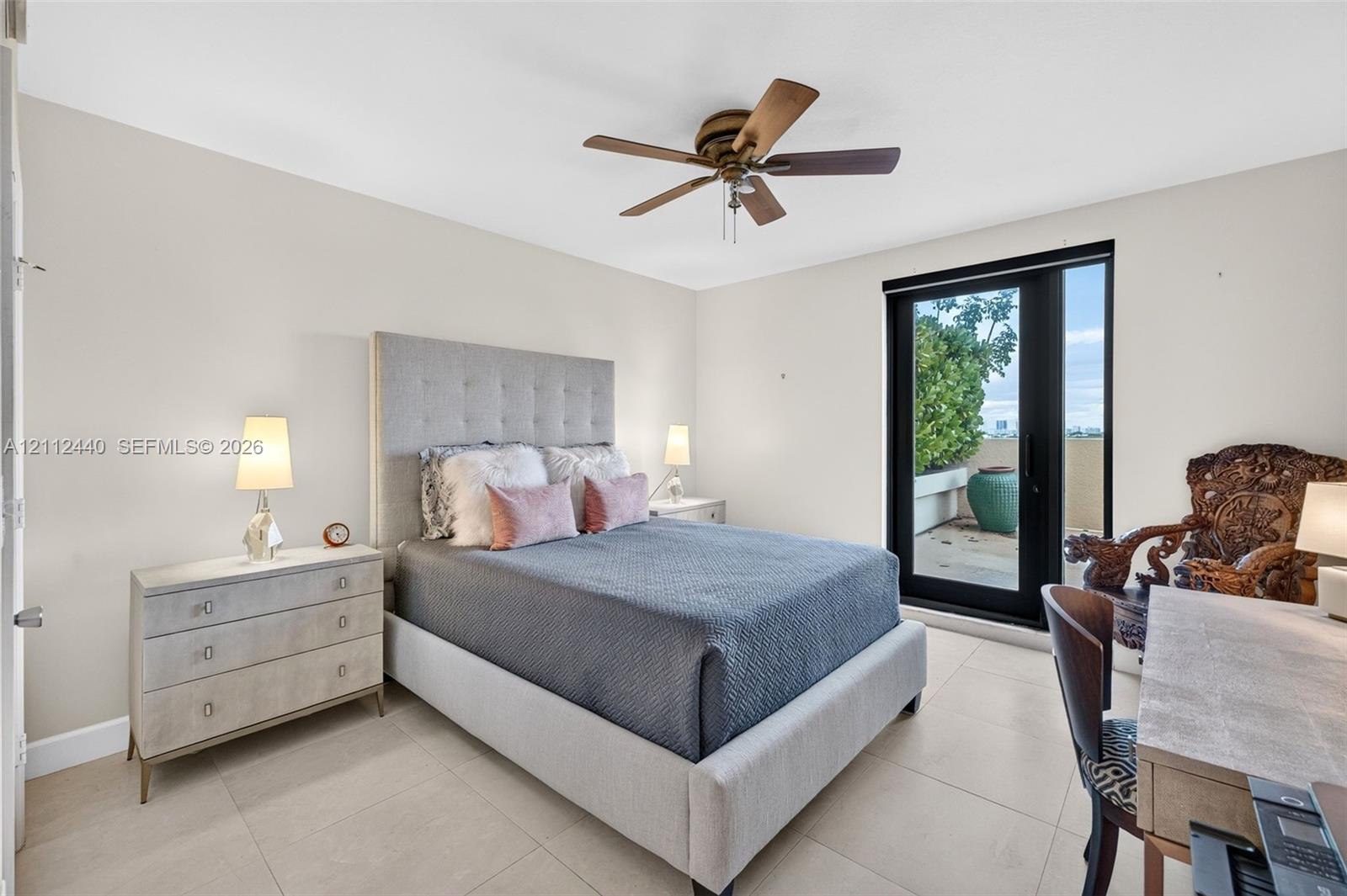Neutral-toned interior featuring large-format porcelain flooring, a ceiling fan with integrated lighting, and full-height glass door providing exterior access to another oversized private terrace