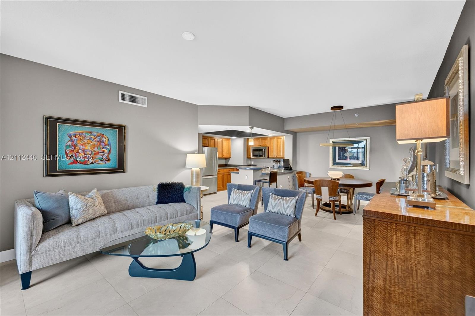 Open-concept interior featuring large-format porcelain flooring, and a kitchen equipped with upgraded wood cabinetry